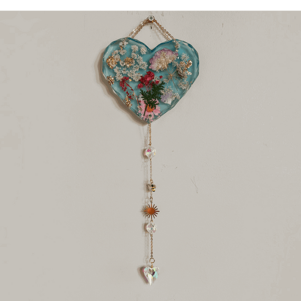 Glow in the dark heart suncatcher handcrafted in blue resin with pressed wildflowers, gold leaf, and decorative gold chain with crystal drops.