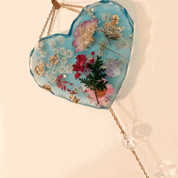 Blue resin glow in the dark heart suncatcher with real pressed wildflowers, gold leaf accents, and a gold chain with crystal drops.