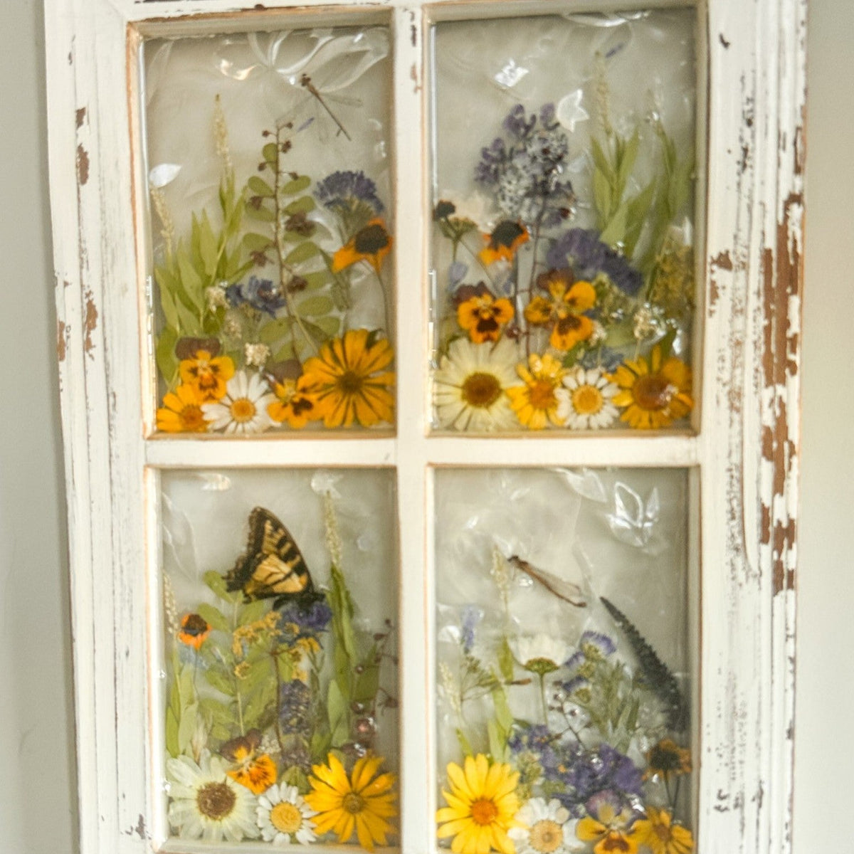 Pressed Flower Window Frame with white distressed wood, four resin panes containing real pressed yellow, white, and purple flowers, and a swallowtail butterfly and dragonflies.