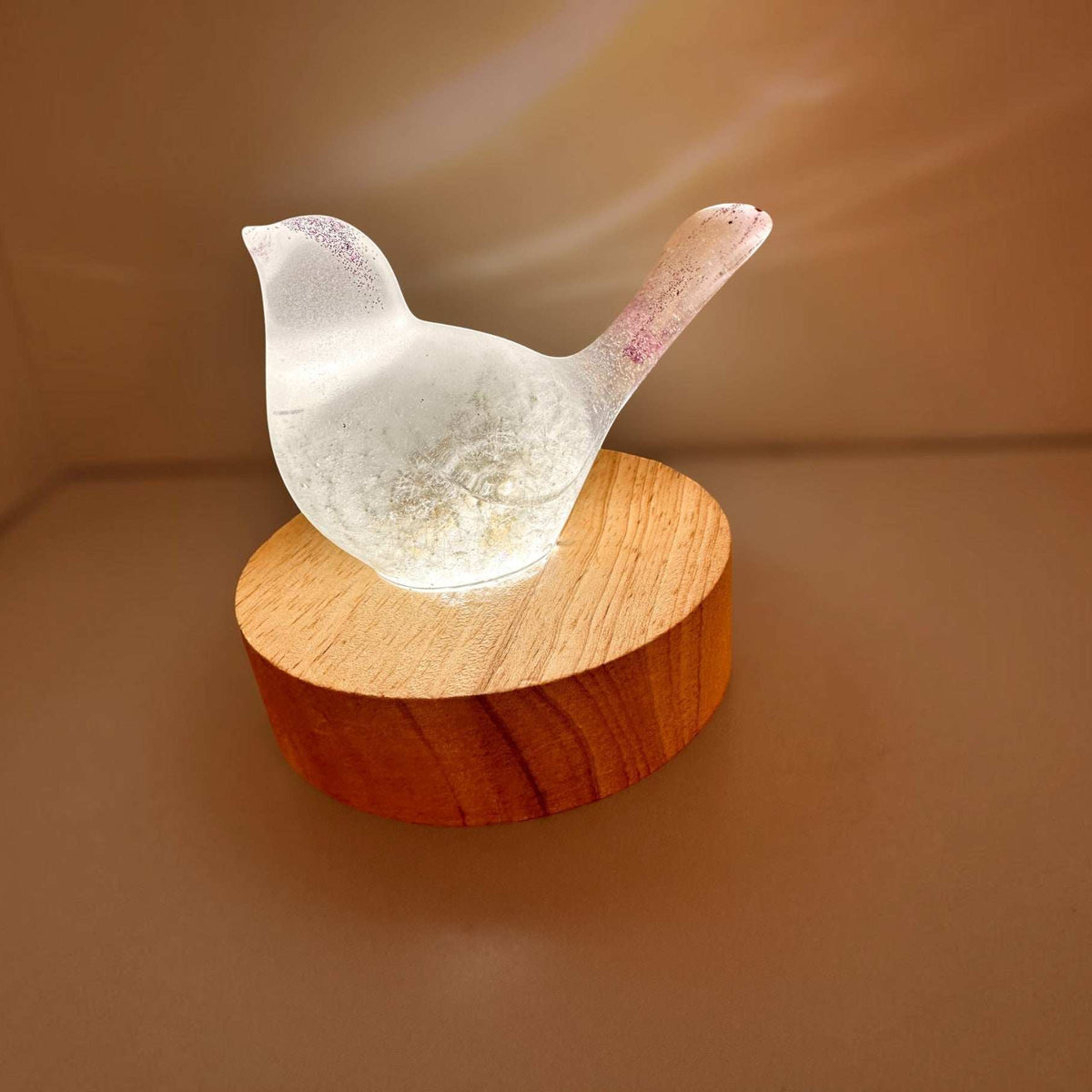 Glow in the Dark Resin Bird, milky white with violet glitter and a translucent dandelion puff, on a wood base