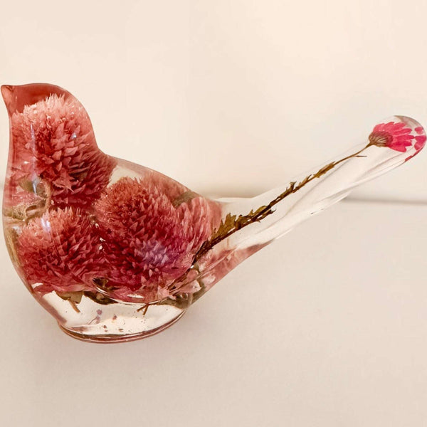 Dried flower resin bird with a clear body, rosy pink clover blossoms, and delicate stems forming the tail
