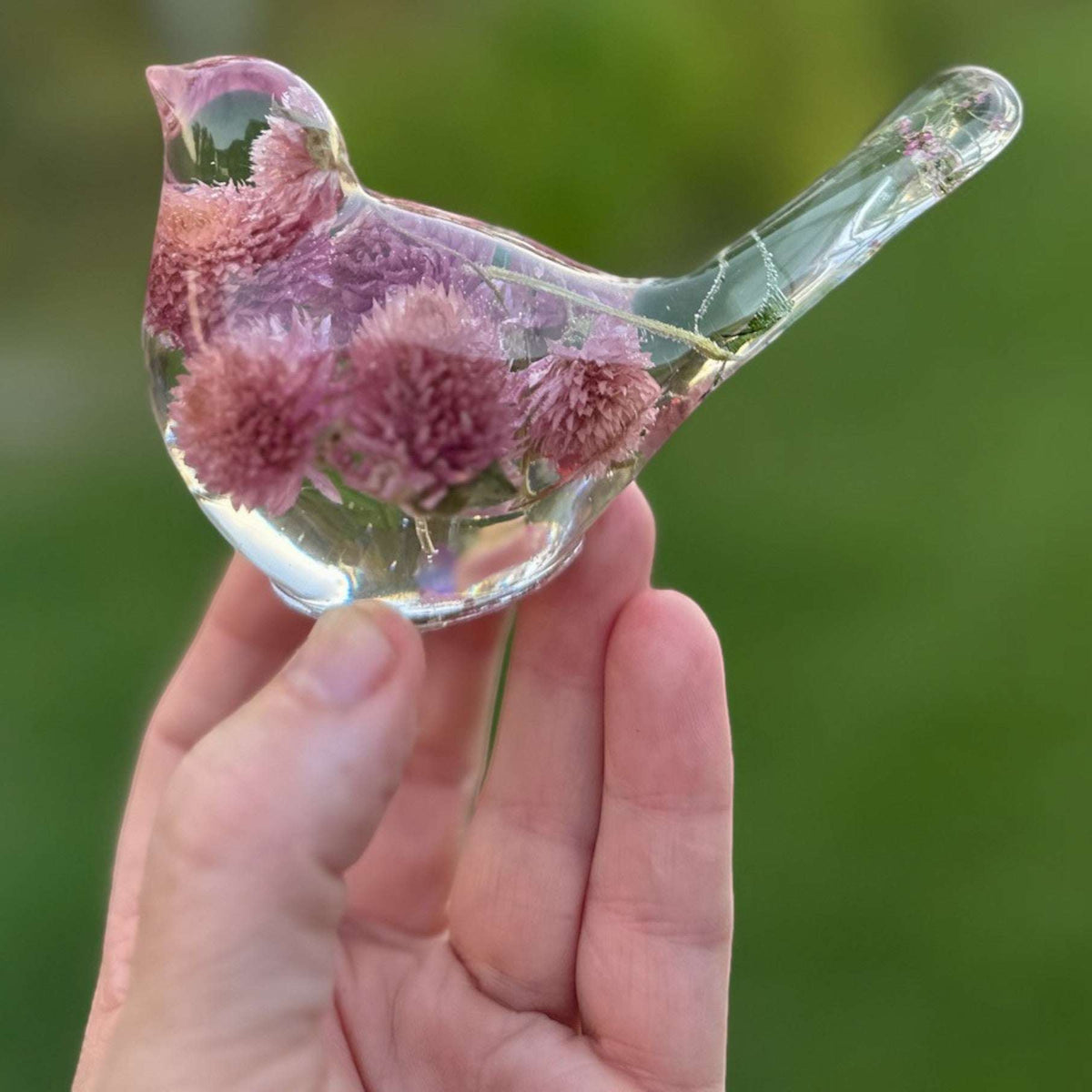 Dried flower resin bird with clear resin, pink and lilac clover blossoms, and delicate stems in the tail