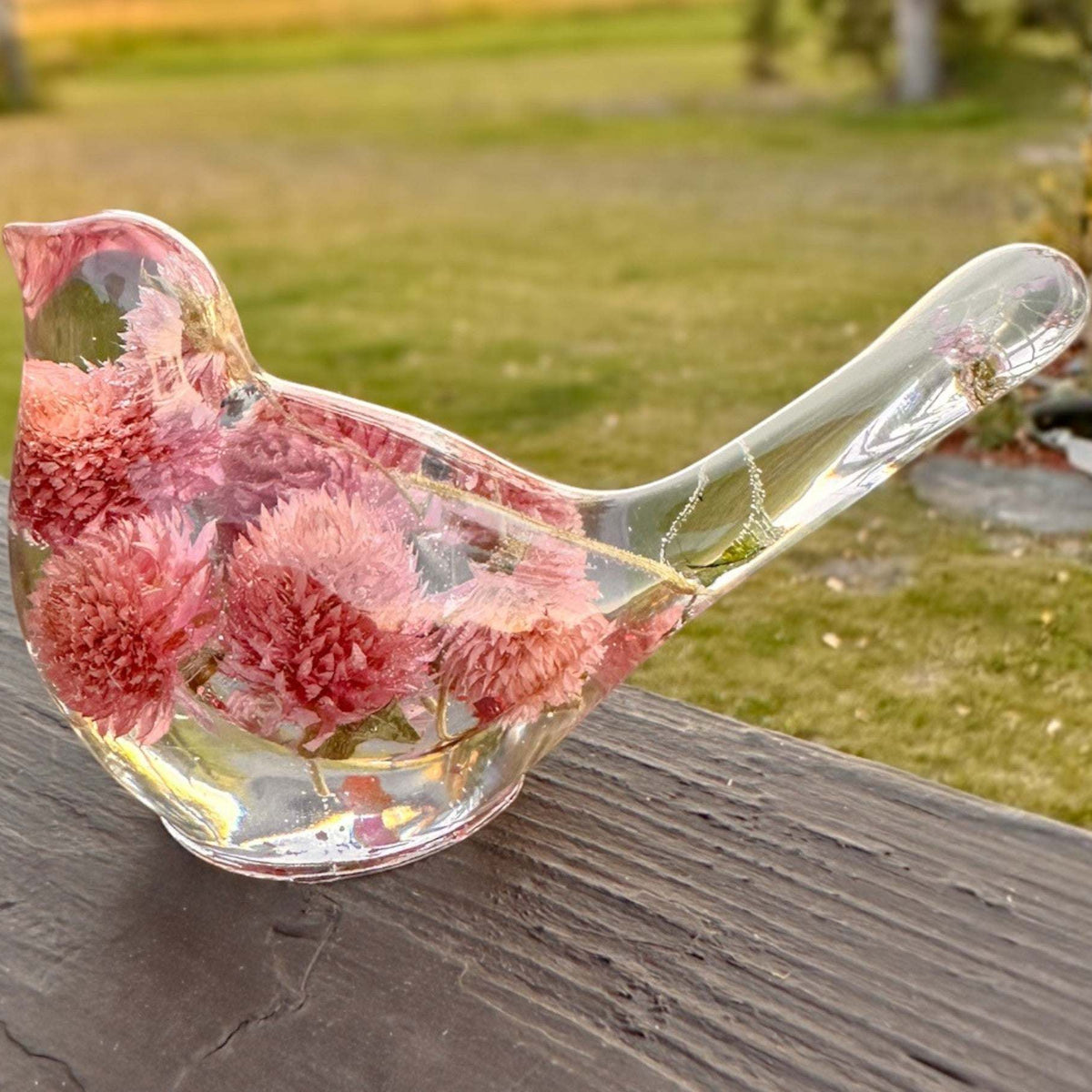 Dried flower resin bird with clear glass-like body, rosy pink clover blossoms, and delicate stems in the tail