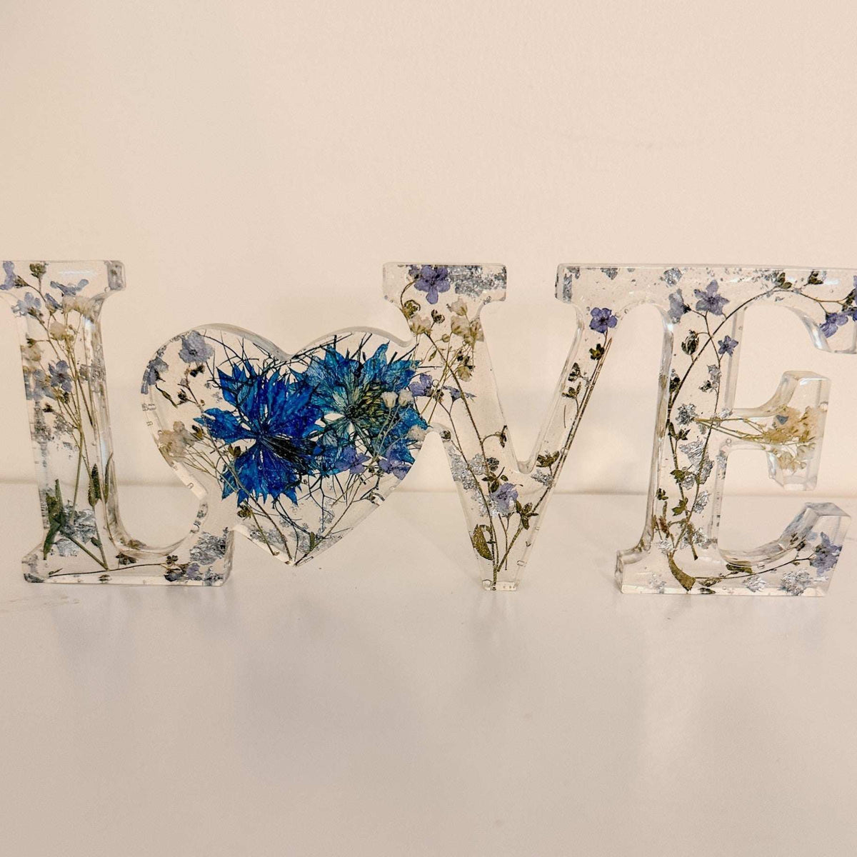 forget me not resin love sign in clear resin with pressed blue flowers, greenery, and silver leaf detailing