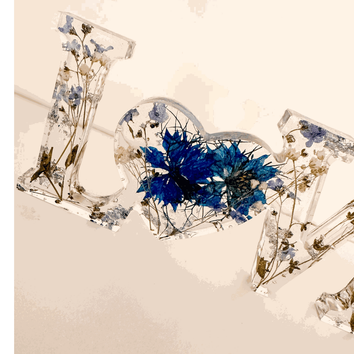 Forget me not resin love sign in clear resin, featuring blue pressed flowers, greenery and a heart-shaped O