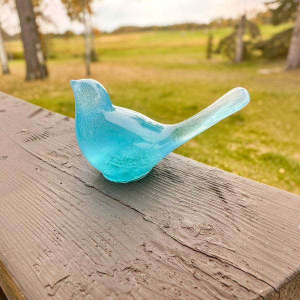 Teal glow resin bird decor, a translucent turquoise glass-like songbird with a long raised tail and smooth finish