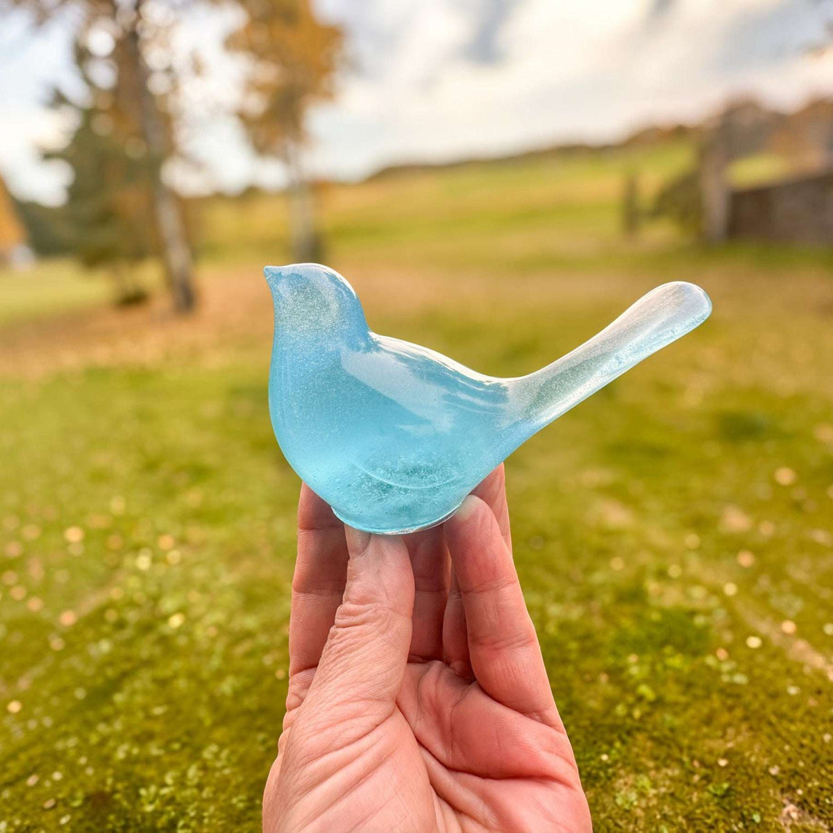 Teal glow resin bird decor, translucent aqua-blue resin songbird with a smooth curved tail and rounded body