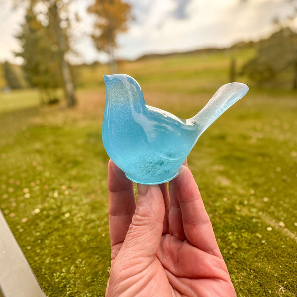 Teal glow resin bird decor, a translucent blue-green resin songbird with a raised tail and smooth glossy finish