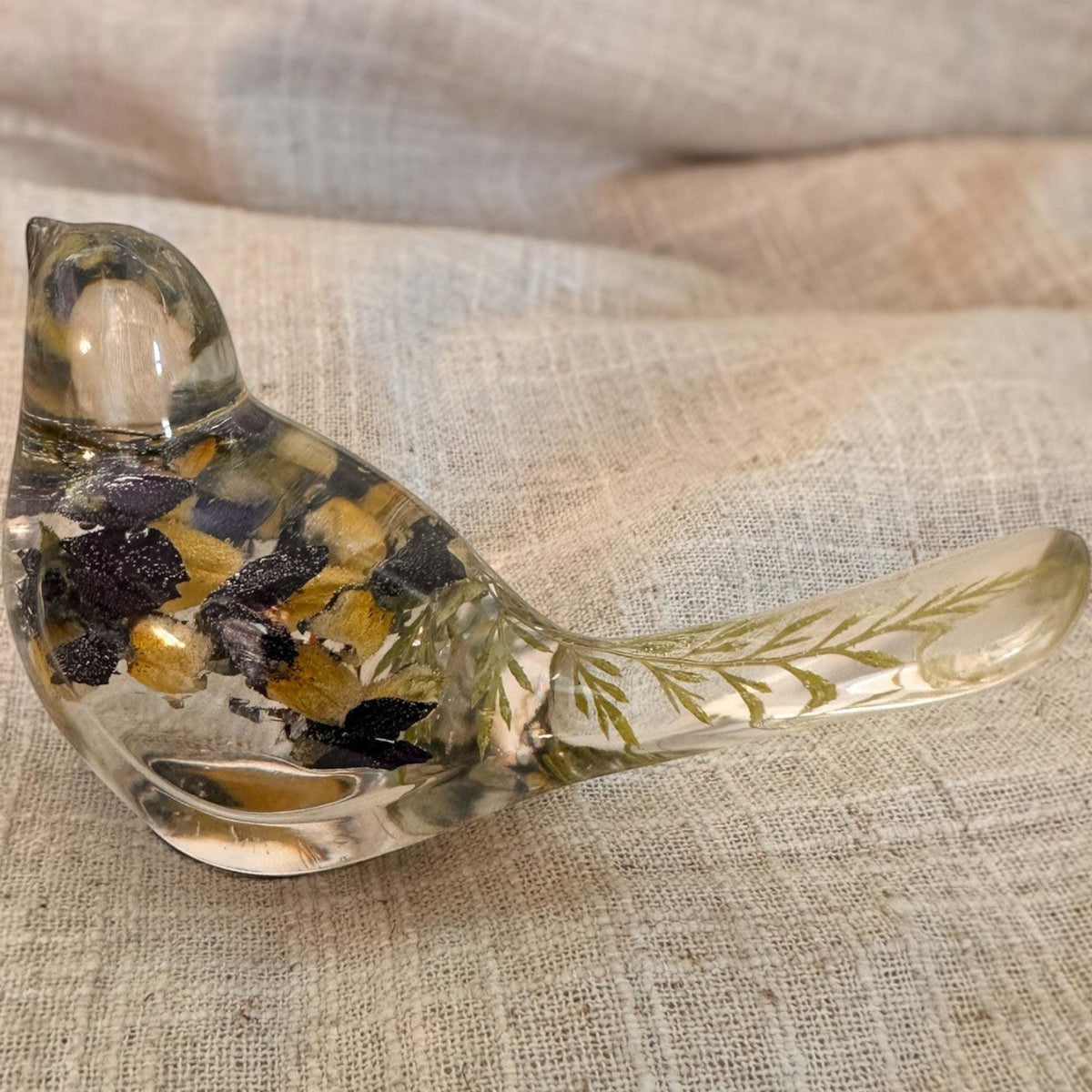 Blue Lupine resin bird decor, clear resin songbird with dark purple and golden yellow flowers and green foliage in its tail
