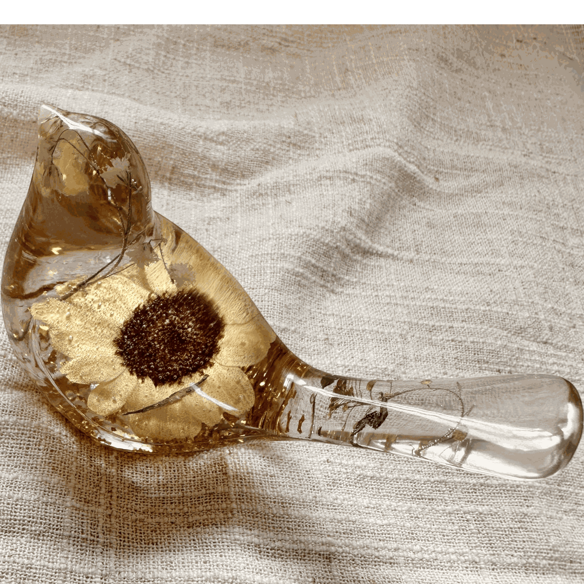 Handmade resin bird decor featuring a preserved Sunflower with a dark center, gold leaf, and clear amber-tinted resin.