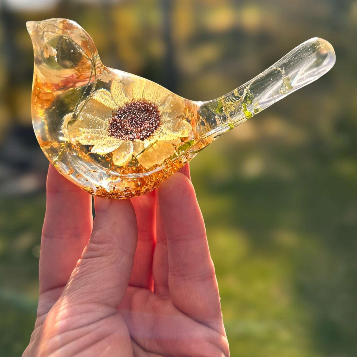 Resin bird decor featuring a clear glossy body with a pressed yellow Sunflower, gold accents, and delicate botanicals.