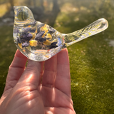 Blue Lupine resin bird decor in clear resin with embedded dark blue and yellow botanicals and a slender, leafy tail.