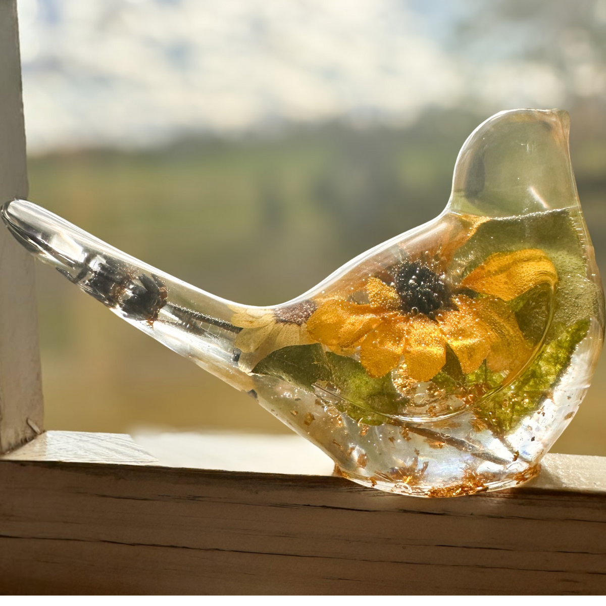 Sunflower Songbird resin bird decor with clear body, golden yellow sunflower, green foliage and gold flecks.
