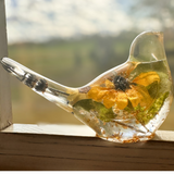 Sunflower Songbird resin bird decor with clear body, golden yellow sunflower, green foliage and gold flecks.