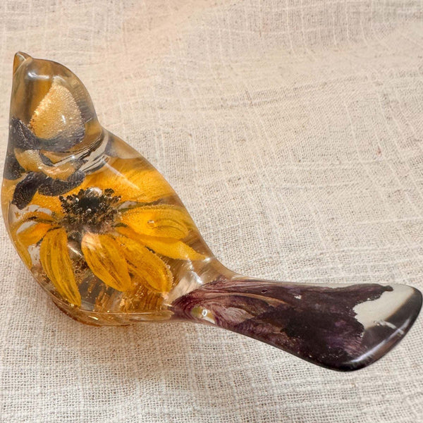Sunflower lupine resin bird decor with clear amber resin, golden sunflower petals, dark centre and deep plum tail accents.