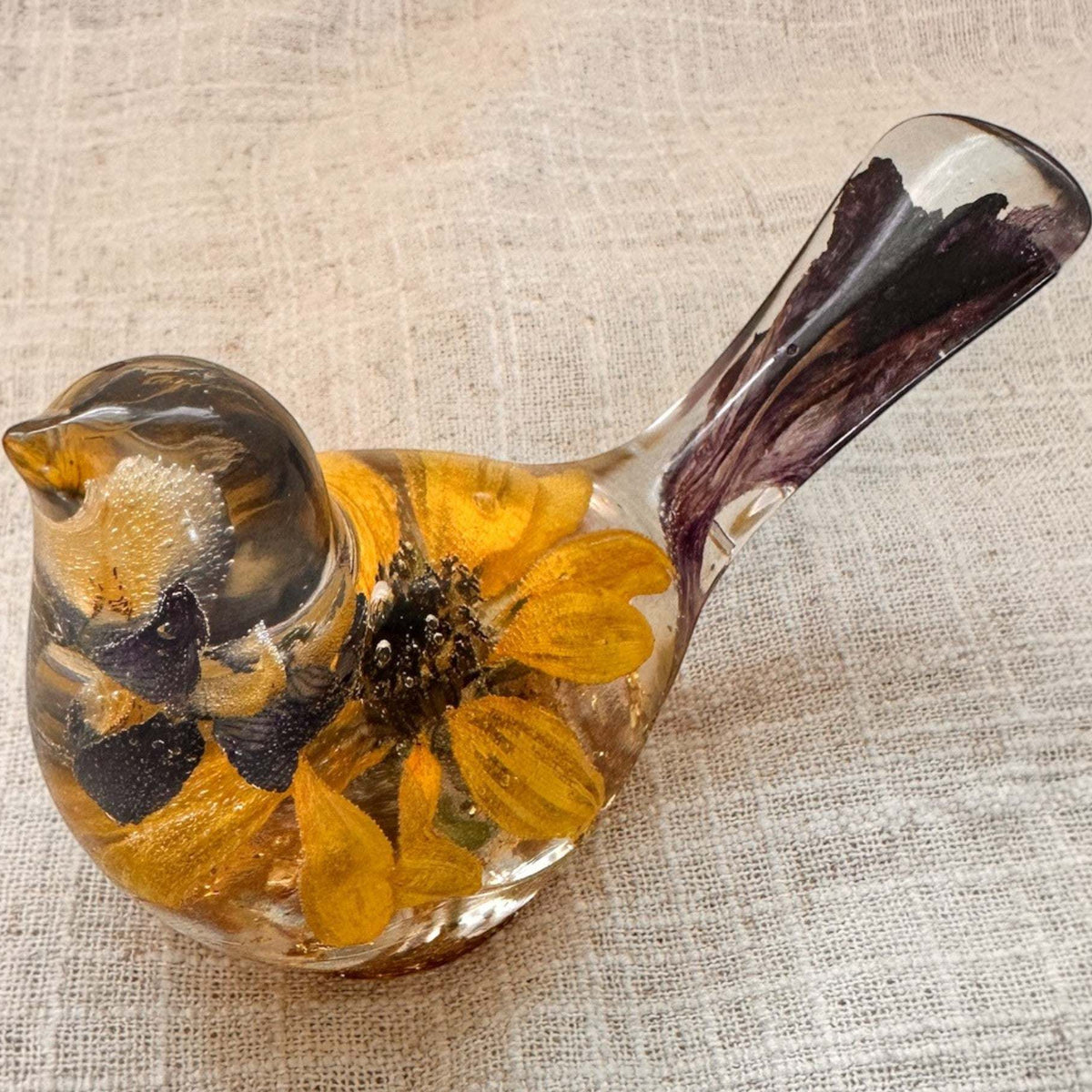 Sunflower lupine resin bird decor with a clear body, golden sunflower petals, dark centre and deep purple tail accents.
