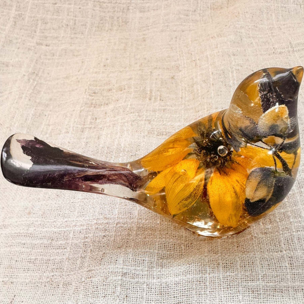 Sunflower lupine resin bird decor with clear glossy resin, vivid yellow sunflower petals, dark seed centre and plum-purple tail accents.