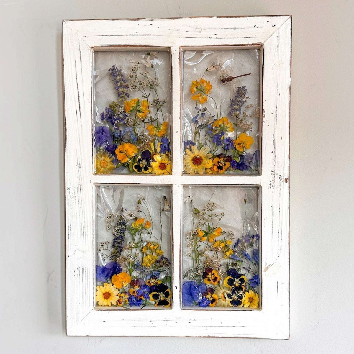 Pressed Flower Window Frame in distressed white wood, with four clear resin panes of colorful pressed wildflowers and a dragonfly.