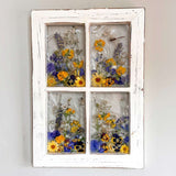 Pressed Flower Window Frame in distressed white wood, with four clear resin panes of colorful pressed wildflowers and a dragonfly.