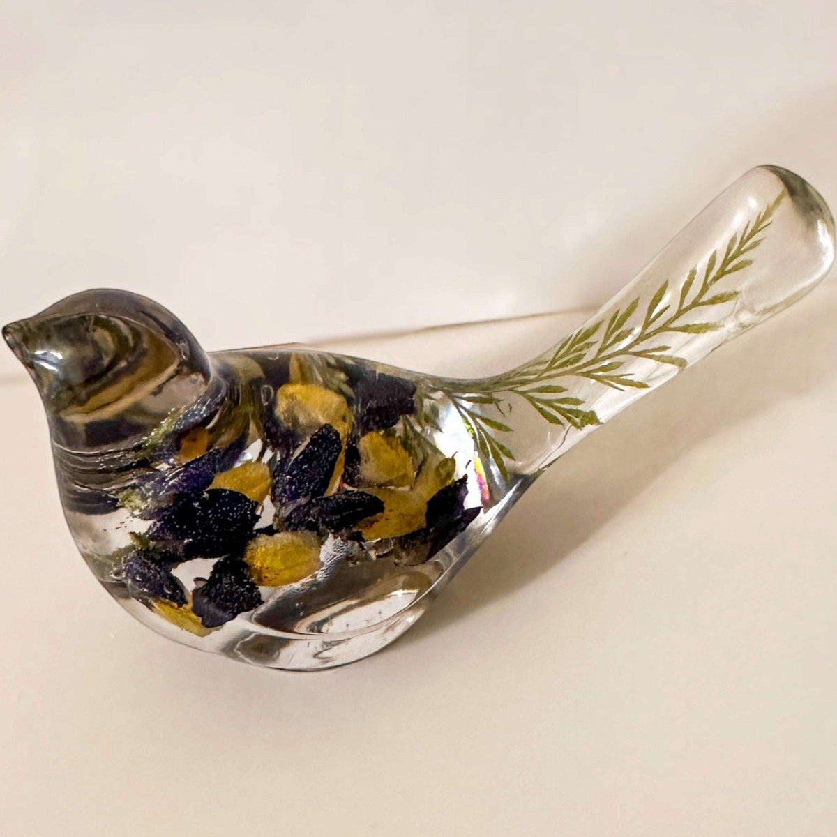 Blue Lupine resin bird decor in clear resin, with deep blue and golden yellow flowers and green botanicals in its tail.