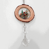 Suncatcher made from a natural wood slice with bark edge, miniature forest botanicals in resin and clear crystal drops