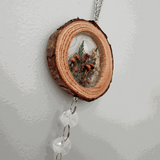Suncatcher with a natural bark-edged wood slice, clear resin woodland botanicals, and faceted crystal drops