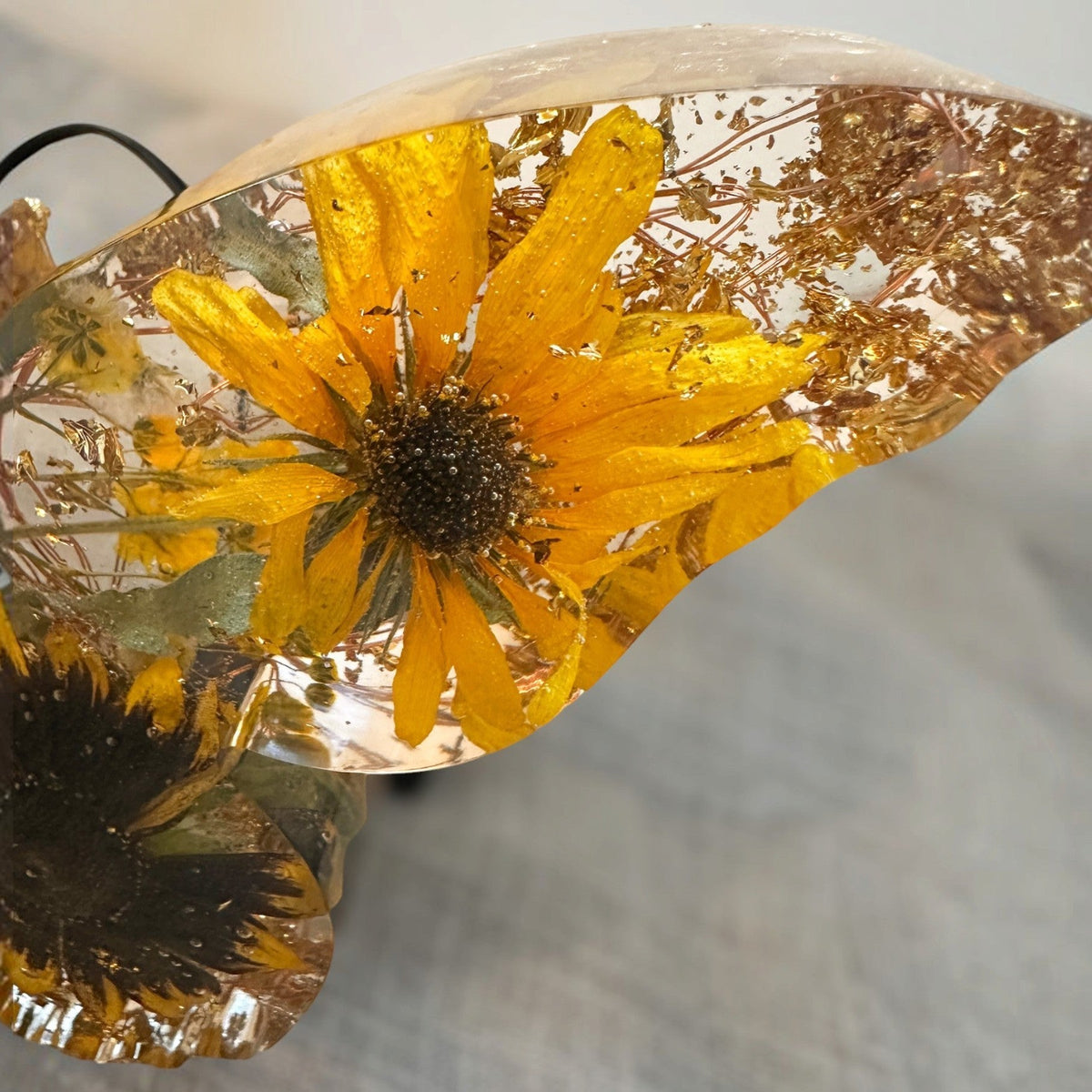 Light up resin butterfly decor with clear resin wings, pressed golden sunflowers, dark centers, green leaves and gold flecks.