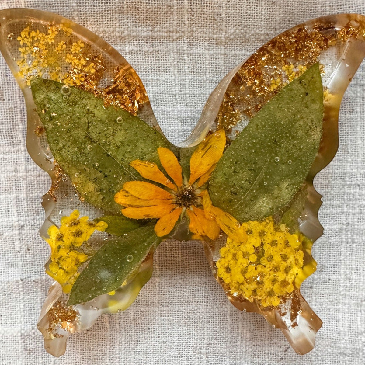 Light up resin butterfly decor in clear resin with green leaves, yellow flowers, orange petals, and gold leaf