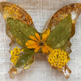 Light up resin butterfly decor in clear resin with green leaves, yellow flowers, orange petals, and gold leaf