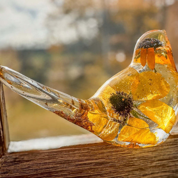 Golden Meadow resin bird with a clear glossy body, preserved golden flower petals, dark centres and shimmering gold accents.