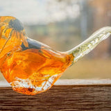 Resin bird ornament in clear resin with vivid orange and yellow preserved flower petals, a dark centre and clear tail; Golden Meadow design.