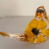 Golden Meadow resin bird with clear glossy body, preserved yellow black-eyed susan blooms and dark centres, plus gold accents.