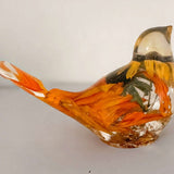 Golden Meadow resin bird with a clear glossy body, orange and gold botanical details, and a curved tail and crest.