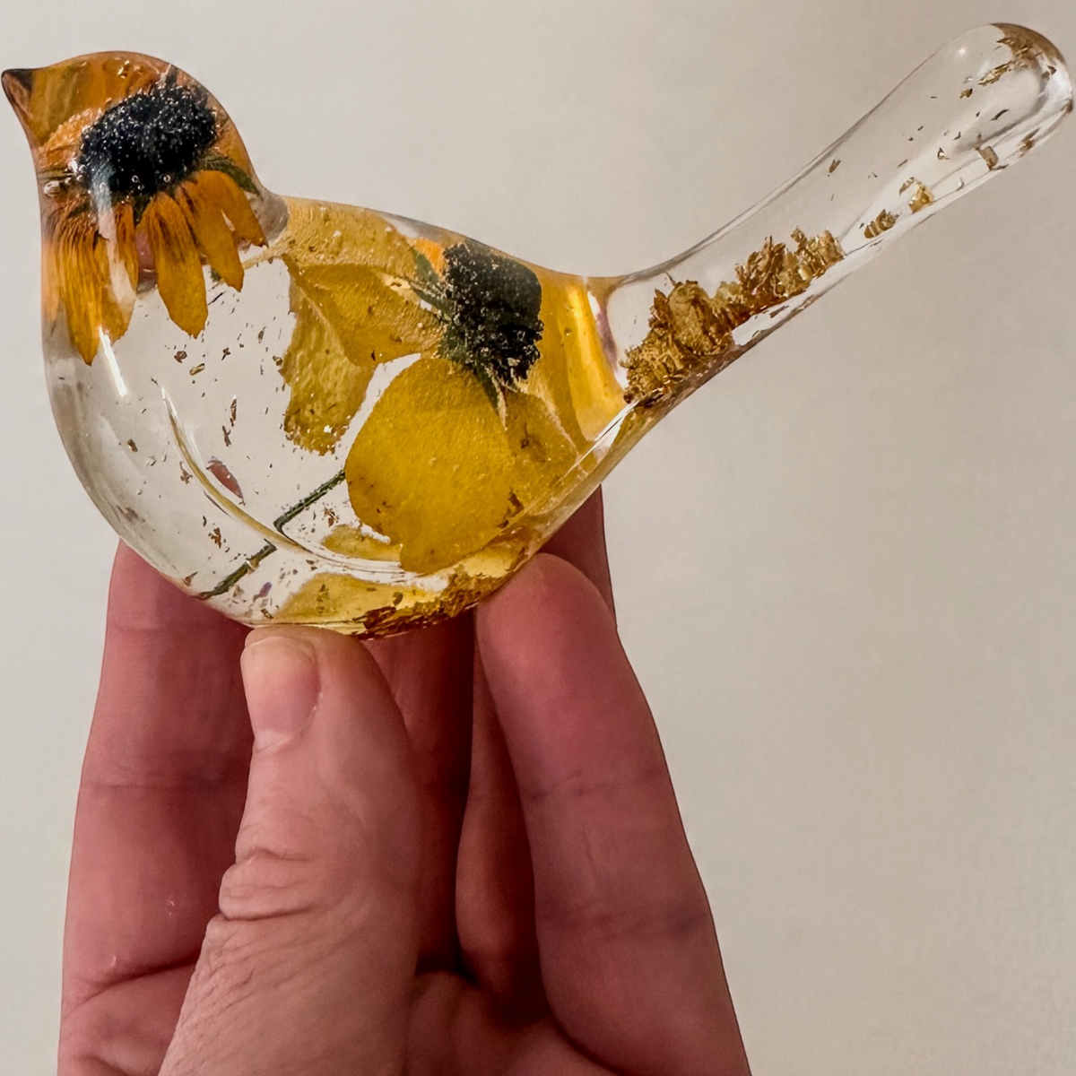 Resin bird ornament Golden Meadow in clear resin with golden yellow preserved flowers, dark centers, and gold leaf accents.