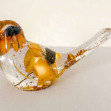 Resin bird with a clear body, Golden Meadow yellow flowers, dark centers and shimmering gold leaf accents.