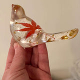 Maple Leaf Songbird in clear resin with a red maple leaf and scattered gold accents, shaped as a smooth bird figurine.