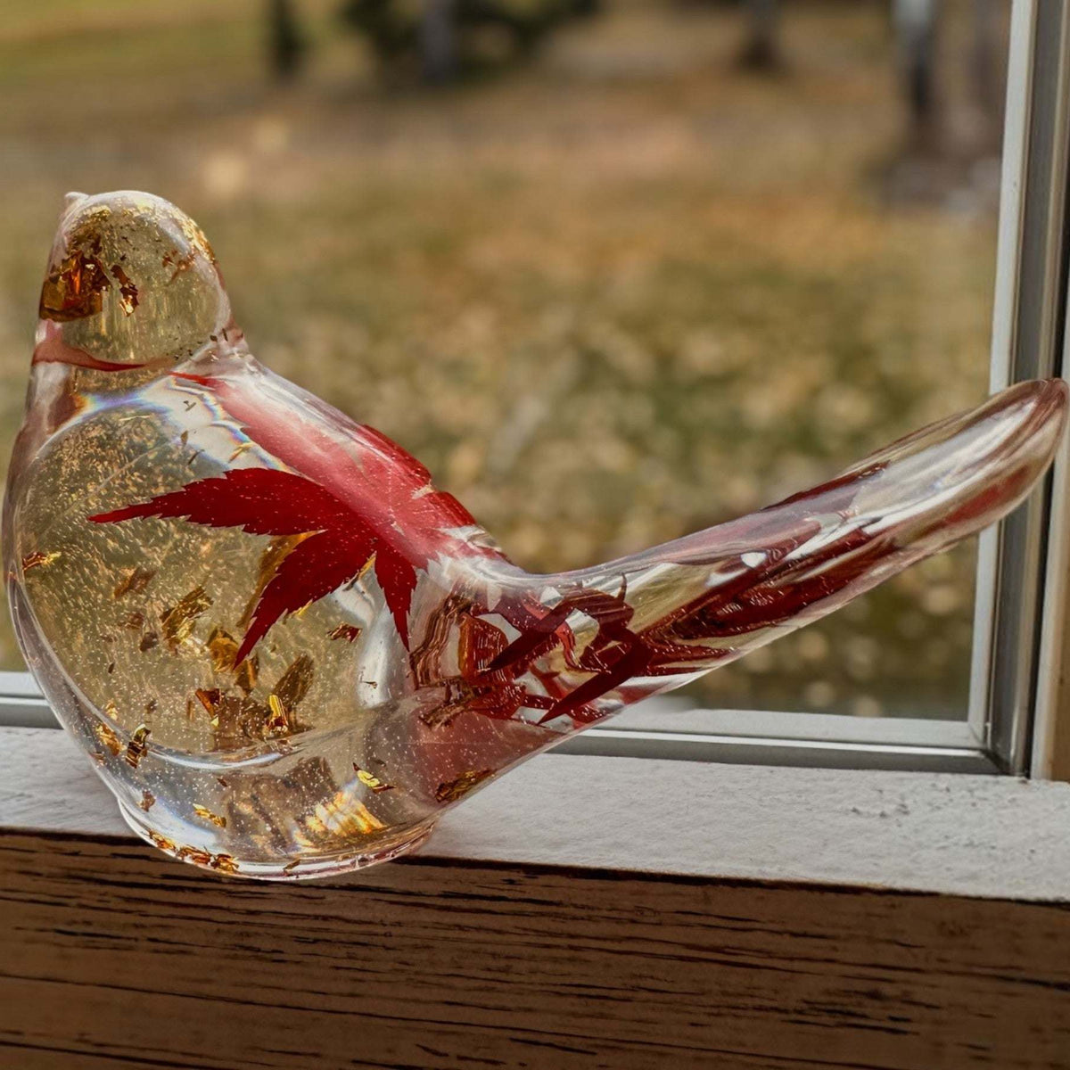 Maple Leaf Songbird resin bird with a clear glass-like body, red maple leaf pieces, and shimmering gold accents.