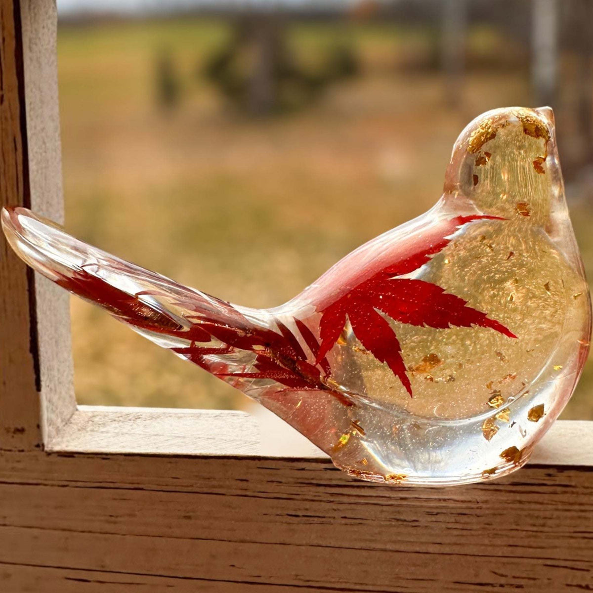 Maple Leaf Songbird in clear resin with a red maple leaf, gold flecks, and a rounded glass-like form.