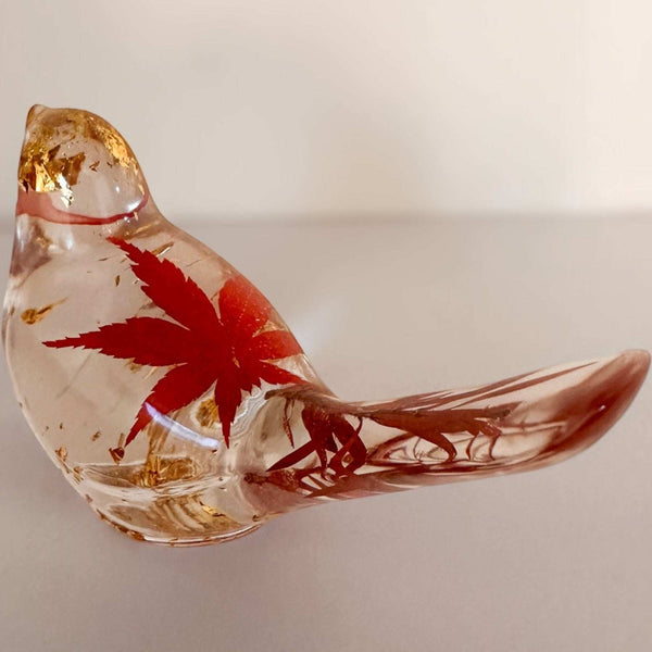 Maple Leaf Songbird resin bird with a clear glass-like body, red maple leaf, and shimmering gold accents.