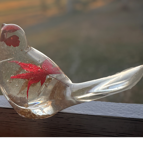 Maple Leaf Songbird in clear resin, with a suspended red maple leaf and subtle gold flecks, handmade with a curved tail.