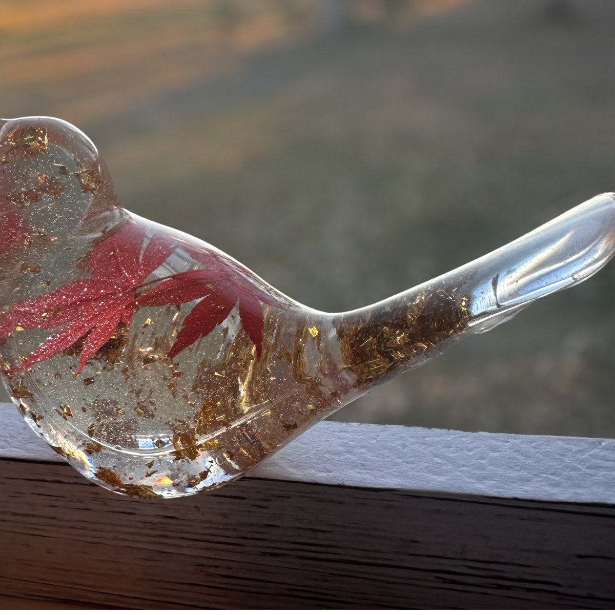 Maple Leaf Songbird in clear resin with a red maple leaf, gold flecks, and a smooth sculpted bird shape.