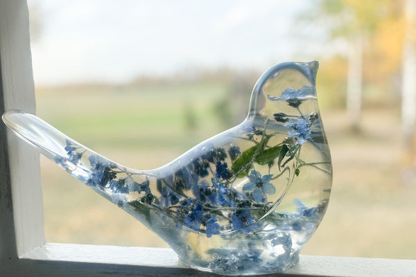 Decorative glass bird with floral design on a windowsill