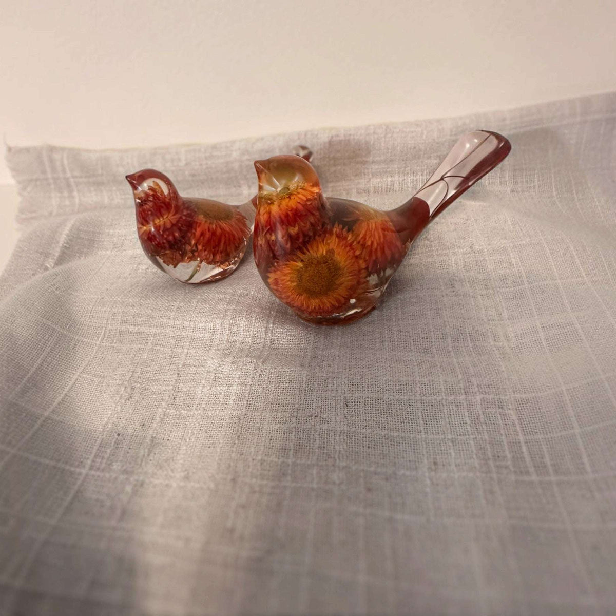 Resin Bird Pair of two clear resin birds with red, orange and yellow dried flowers, copper-toned bases and botanical tails.