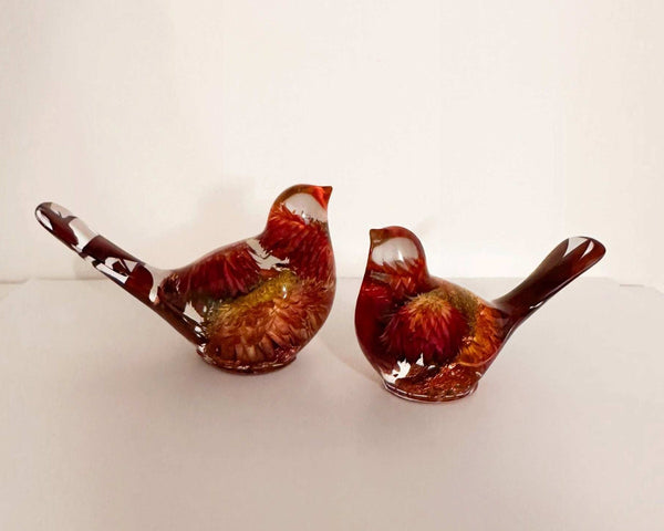 Resin Bird Pair with clear resin bodies, deep red and orange dried flowers, and long decorative tails in two sizes.