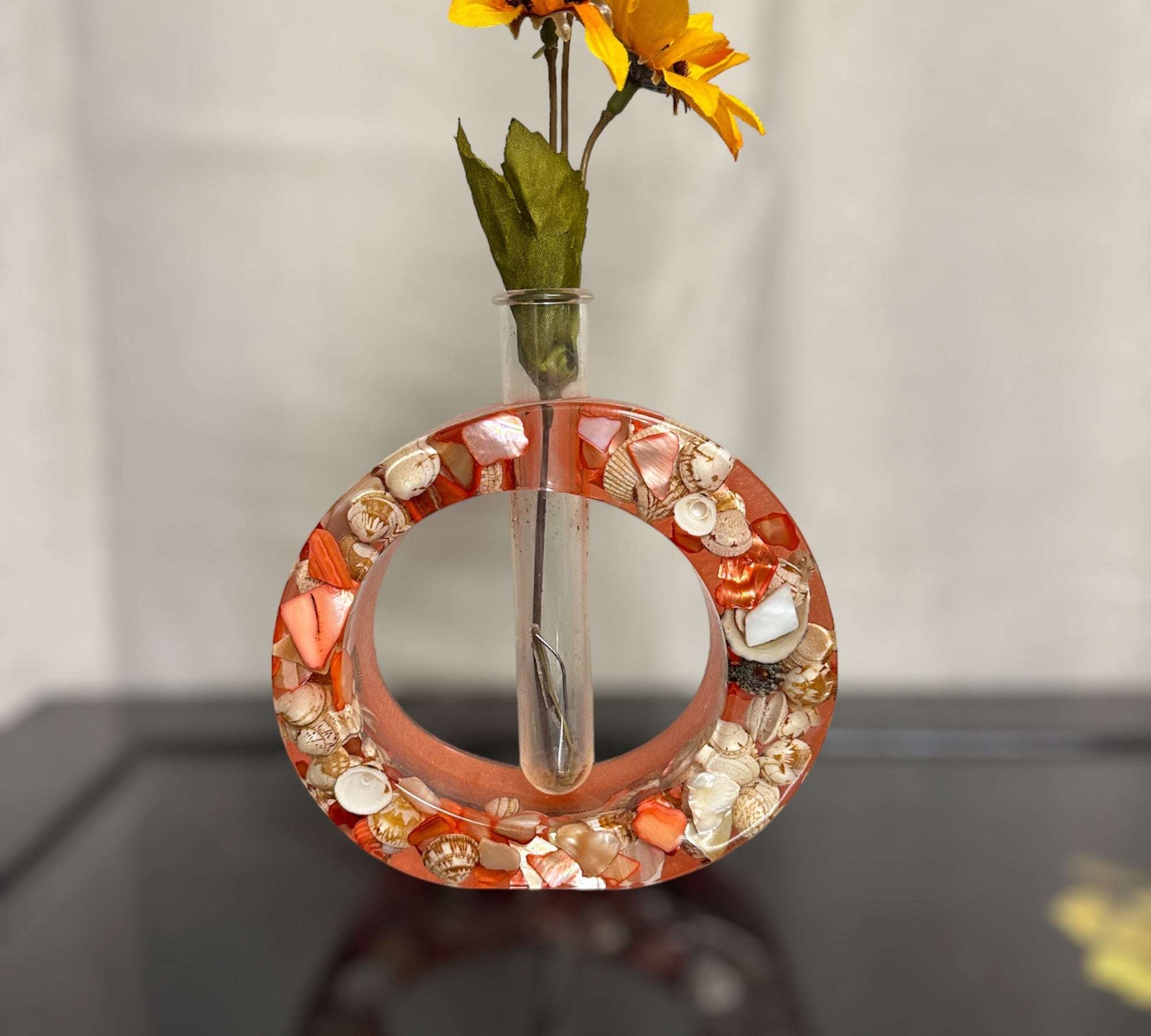 This 5" round Plant Bud Vase is created with two layers of Epoxy Resin. The first layer is clear and filled with real seashells and mother of pearl shells. The backround colour is a beautiful salmon. Comes with a test tube that you can fill with water and set your favourite flower or start your favourite plant