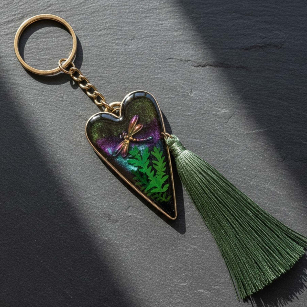 Aurora dragonfly keychain with a silver heart frame, green ferns in purple-green resin, and a long green tassel.