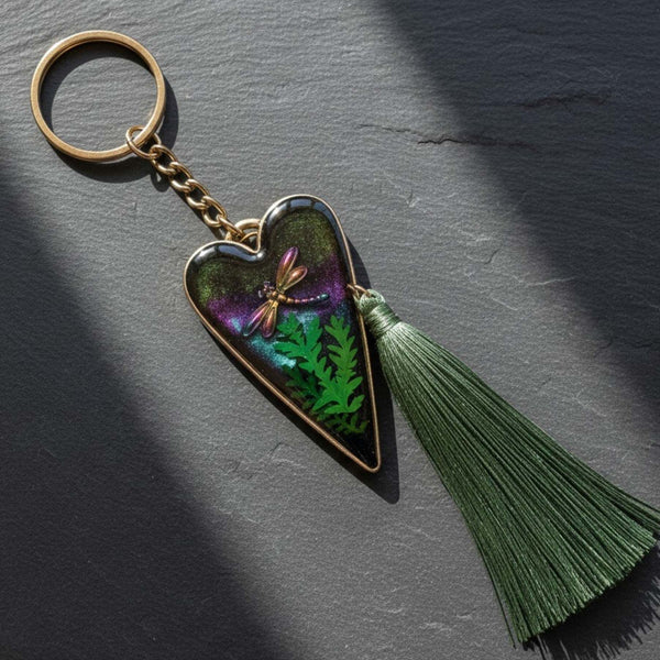 Aurora dragonfly keychain with a silver heart frame, green ferns in purple-green resin, and a long green tassel.