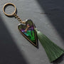 Aurora dragonfly keychain with a silver heart frame, green ferns in purple-green resin, and a long green tassel.