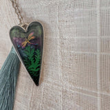 Aurora dragonfly keychain in a silver heart frame, with green ferns, shimmering purple-green resin, and a teal tassel.