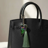Aurora dragonfly keychain with a silver heart-shaped resin charm, green ferns, purple-green shimmer and green tassel.